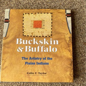 Puede incluir: Un libro titulado "Buckskin & Buffalo" con el subtítulo "The Artistry of the Plains Indians" de Colin F. Taylor. La portada es de color marrón claro con un diseño cuadrado y texto blanco. Los bordes tienen cuentas decorativas.