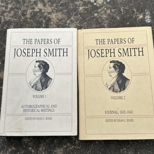 Puede incluir: Dos libros de tapa dura titulados "The Papers of Joseph Smith". El volumen 1 es blanco con texto negro y un retrato. El volumen 2 es beige con texto negro y un retrato. Ambos libros están editados por Dean C. Jessee.