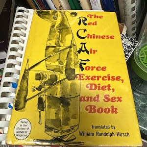 May include: A yellow book titled "The Red Chinese Air Force Exercise, Diet, and Sex Book." The cover features a black and white illustration of a figure with the text in red and black. Translated by William Randolph Hirsch.