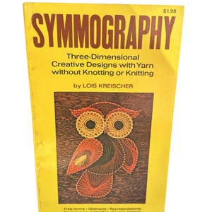 以下が含まれることがあります： 黄色い表紙と茶色の文字が特徴の、ヴィンテージ本「Symmography」。表紙には糸で作られたフクロウのデザインが描かれています。本のサブタイトルは「結び目や編み物を使わない、糸を使った三次元クリエイティブデザイン」です。
