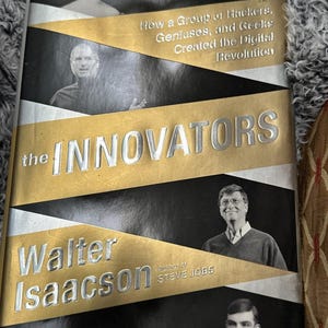 May include: A hardcover book titled "The Innovators" by Walter Isaacson. The cover features images of historical figures and the text "How a Group of Hackers, Geniuses, and Geeks Created the Digital Revolution."