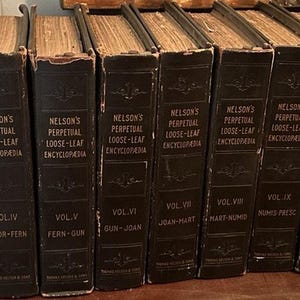 Puede incluir: Una colección de libros antiguos, encuadernados en tapas marrones oscuras con letras doradas. Las lomos muestran el título "Nelson's Perpetual Loose-Leaf Encyclopedia" y los números de volumen. Los libros están dispuestos en fila, sugiriendo un conjunto.