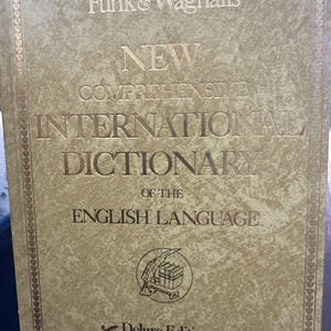 以下が含まれることがあります： 「Funk & Wagnalls New Comprehensive International Dictionary of the English Language Deluxe Edition」というタイトルの金色の本の表紙です。