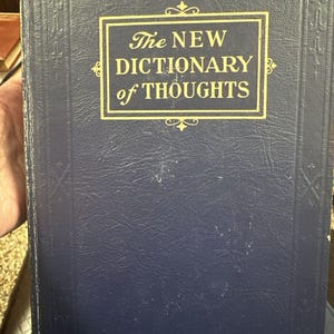 Könnte beinhalten: Ein dunkelblaues Hardcover-Buch mit goldenen Lettern auf dem Einband. Der Titel lautet "The NEW DICTIONARY of THOUGHTS".