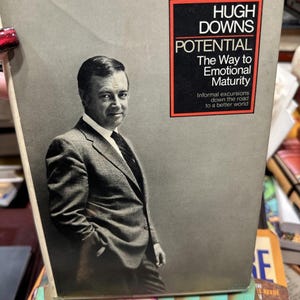 May include: A book cover featuring a black and white image of Hugh Downs in a suit. The title "POTENTIAL The Way to Emotional Maturity" is displayed in red and black text. The book is stacked on top of other books.