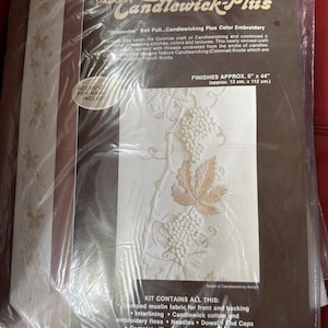 May include: A packaged Candlewick Plus embroidery kit featuring a grapevine design. The kit includes stamped muslin fabric, interlining, embroidery floss, needles, and dowel end caps. Finished size is approximately 5" x 44".