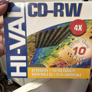 May include: A Hi-Val CD-RW 10-pack in a jewel case. The package is white and blue with the text "CD-RW" in large blue letters. It includes a red circle with "4X" and text indicating 80 minutes, 700 MB capacity, and 1X-4X compatibility.