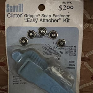 May include: A package of Scovill Clinton Gripper Snap Fastener "Easy Attacher" Kit. The kit includes a blue nylon attacher tool and five silver snaps. The package also includes instructions and the text "No. 16 K".