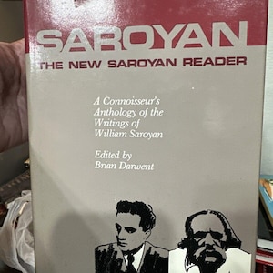 May include: A book cover with the title "SAROYAN THE NEW SAROYAN READER". The cover features a black and white illustration of two men. The text below the title reads "A Connoisseur's Anthology of the Writings of William Saroyan Edited by Brian Darwent".