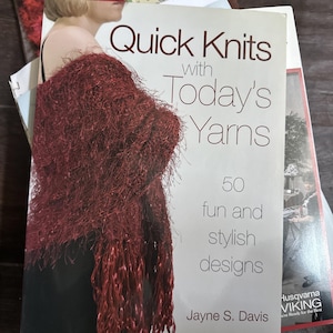 May include: A book titled "Quick Knits with Today's Yarns" featuring 50 fun and stylish designs. The cover shows a woman wearing a burgundy fringed scarf. The book is by Jayne S. Davis.
