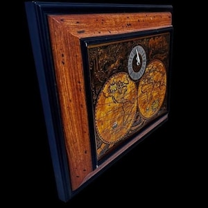 May include: A framed wall clock with a vintage world map design. The clock face is round with Roman numerals. The frame is a combination of dark blue and wood tones, creating a classic aesthetic. The clock's hands indicate the time.