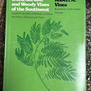 Puede incluir: Un libro verde titulado "Trees, Shrubs, and Woody Vines of the Southwest" de Robert A. Vines. La portada presenta una ilustración verde de una planta. El libro es una guía para los estados de Arkansas, Luisiana, Nuevo México, Oklahoma y Texas.
