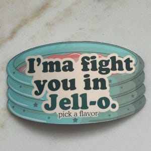 Może przedstawiać: Okrągła naklejka z turkusową obw&oacute;dką i napisem "I'ma fight you in Jell-o. pick a flavor" w kolorze białym i ciemnoturkusowym. Naklejka ma warstwową konstrukcję z r&oacute;żowym i białym wnętrzem.