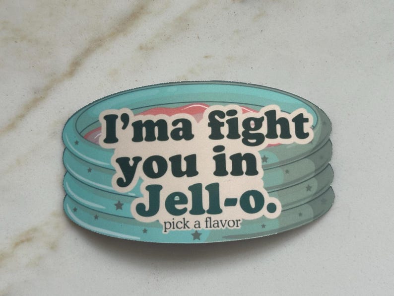 Może przedstawiać: Okrągła naklejka z turkusową obw&oacute;dką i napisem "I'ma fight you in Jell-o. pick a flavor" w kolorze białym i ciemnoturkusowym. Naklejka ma warstwową konstrukcję z r&oacute;żowym i białym wnętrzem.