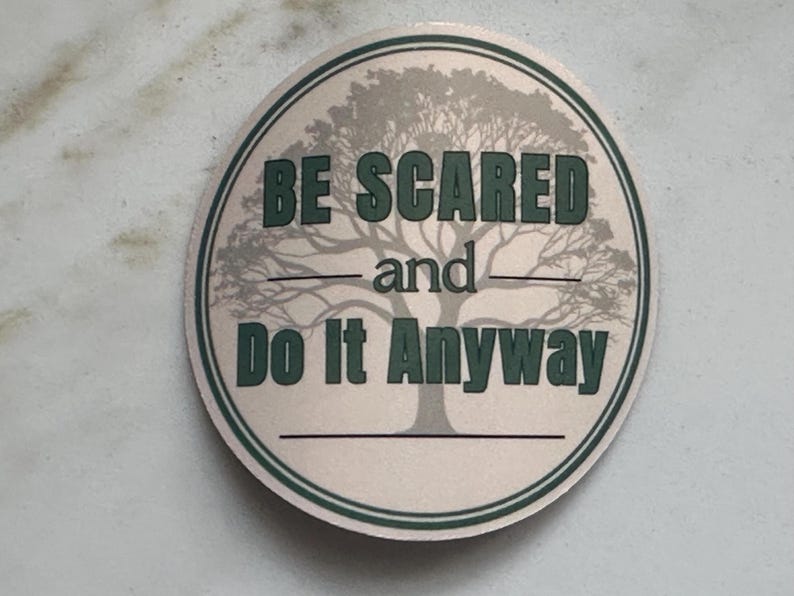 Może przedstawiać: Okrągła naklejka z jasnobeżowym tłem i zieloną obw&oacute;dką. Naklejka zawiera grafikę drzewa i tekst "BE SCARED and Do It Anyway" w zielonych literach.