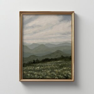 Peut inclure: Peinture de paysage encadr&eacute;e repr&eacute;sentant une cha&icirc;ne de montagnes sous un ciel nuageux. L'&oelig;uvre est dans un cadre dor&eacute;. Le premier plan montre un champ de fleurs blanches, avec des collines et des montagnes vertes en arri&egrave;re-plan.