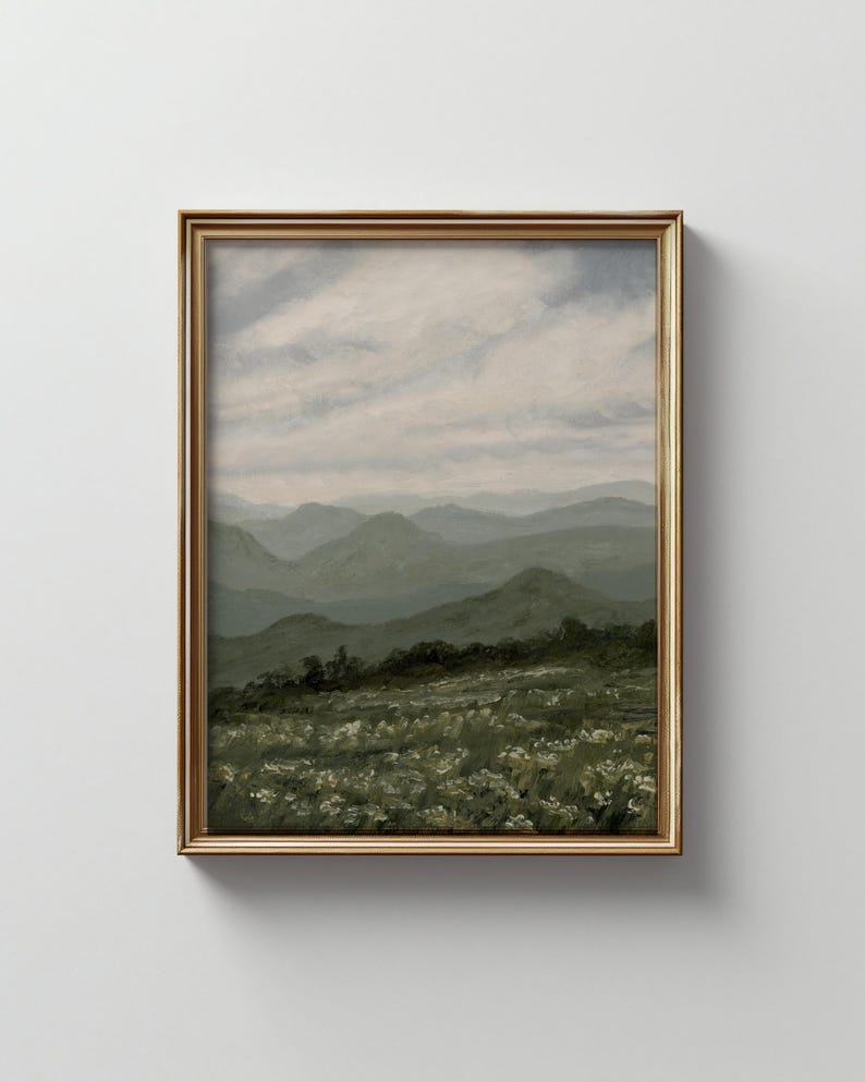 Peut inclure: Peinture de paysage encadr&eacute;e repr&eacute;sentant une cha&icirc;ne de montagnes sous un ciel nuageux. L'&oelig;uvre est dans un cadre dor&eacute;. Le premier plan montre un champ de fleurs blanches, avec des collines et des montagnes vertes en arri&egrave;re-plan.