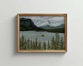May include: A framed painting of a mountain lake scene with snow-capped mountains in the background, a small island in the middle of the lake, and a row of evergreen trees in the foreground.