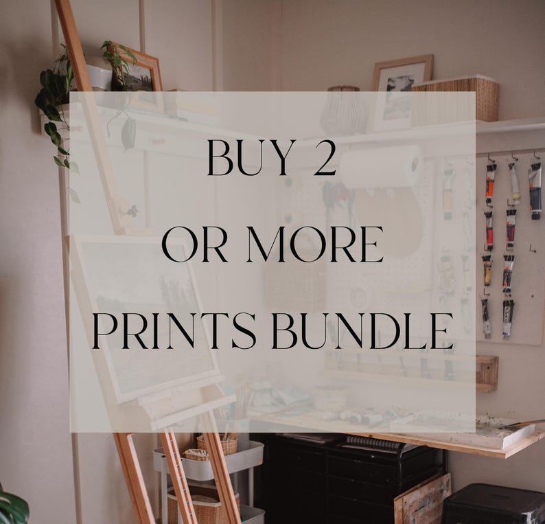 May include: A white sign with black text that reads "BUY 2 OR MORE PRINTS BUNDLE". The sign is in front of a wooden easel with a painting on it. There are paint tubes and other art supplies in the background.