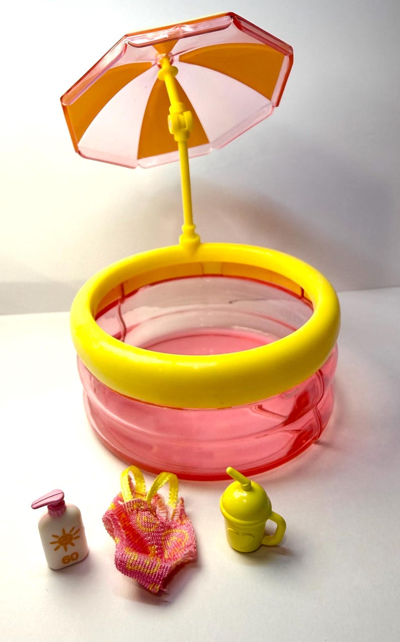 May include: A miniature playset featuring a pink and yellow swimming pool with a yellow parasol. Accessories include a swimsuit, sunscreen, and a yellow drink cup. The set is designed for imaginative play.