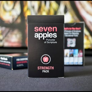 May include: A black box with the words "seven apples" and "Pictures of Scripture" in white text. The box also has a red apple icon and the words "STRENGTH PACK" in white text.