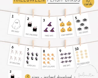 Puede incluir: Tarjetas didácticas de Halloween con ilustraciones de fantasmas, calderos, sombreros, calabazas, arañas, esqueletos, gatos, piruletas, murciélagos y telarañas. Las tarjetas están numeradas del 1 al 10 y cuelgan de una cuerda. El texto dice "Halloween Flash Cards".