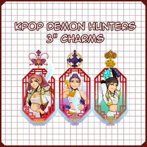 May include: Three 3-inch KPOP Demon Hunters charms. Each charm features a character illustration within a red, ornate frame. The charms have different decorative toppers and are set against a grid background.