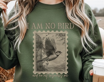 May include: Green sweatshirt with the text "I AM NO BIRD" above a postage stamp design featuring a bird in flight. The text "and no net ensnares me" is below the stamp. The sweatshirt is a solid green color.