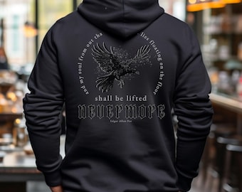 Könnte beinhalten: Schwarzer Kapuzenpullover mit einem grafischen Aufdruck eines fliegenden Rabens mit dem Text "And my soul from out that  lies floating on the floor shall be lifted Nevermore Edgar Allan Poe"