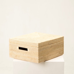 Op de afbeelding: Een rechthoekige opbergdoos gemaakt van lichtbeige gevlochten materiaal. De doos is voorzien van een bijpassend deksel met een geometrisch patroon en een rechthoekige uitgesneden handgreep aan de voorzijde voor een strak en gestructureerd uiterlijk.