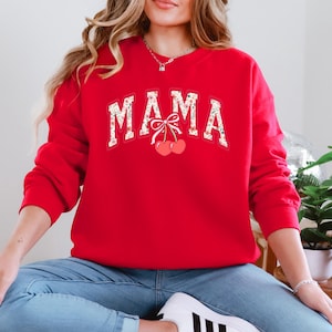 Może przedstawiać: Czerwona bluza z nadrukiem "MAMA" w kwiatowym wzorze i dwiema wiśniami z kokardką.