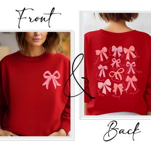 May include: A red crewneck sweatshirt featuring a single light pink bow graphic on the front left chest. The back of the sweatshirt displays a collection of various light pink and dark pink bow illustrations accompanied by small cursive text.