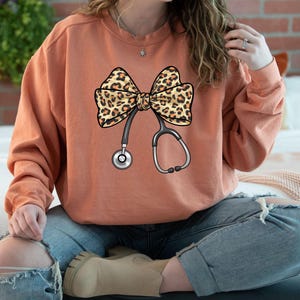 Comfort Colors® Nurse Stethoscope Sweatshirt, Leopard Stethoscope Sweatshirt, Nurse Gift, Coquette Bow Nurse Sweatshirt, Leopard Bow Sweater