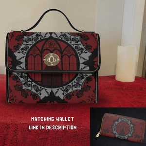 Może przedstawiać: Czarna i czerwona torebka z gotyckim wzorem przedstawiającym okno z witrażem i motywem kwiatowym. Torebka ma górny uchwyt i pasujący portfel.