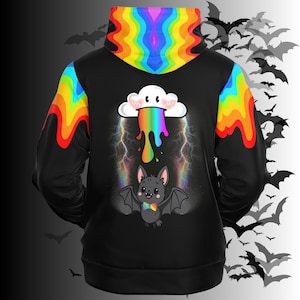 May include: A black hoodie featuring a rainbow-colored hood lining and sleeve accents. The back displays a graphic of a white cloud with a rainbow drip, positioned above a small gray bat wearing a rainbow bowtie, surrounded by lightning.