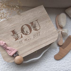 Peut inclure: Une tasse en céramique blanche avec une anse noire et l'inscription "But First, Coffee" en gras noir. La tasse est posée sur un fond flou, suggérant un cadre chaleureux.