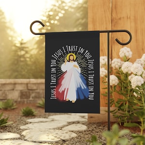 May include: A black garden flag with a white image of Jesus Christ with the words "Jesus I trust in you" repeated around the image.