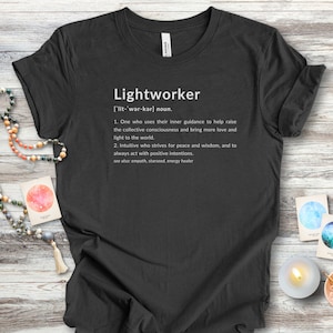 May include: A black t-shirt with a white graphic design that defines the word "Lightworker" and its meaning. The definition includes the phrase "inner guidance" and "collective consciousness".