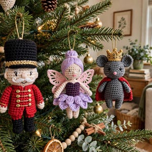 May include: Three crocheted ornaments hanging from a tree: a soldier in a red uniform and black hat, a fairy with lavender hair and wings, and a gray mouse wearing a gold crown and red cape. Each figure is suspended by a thin gold cord.