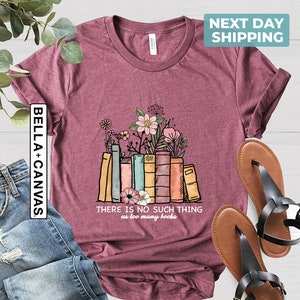 May include: A maroon t-shirt with a graphic of a stack of books with flowers on top. The text "THERE IS NO SUCH THING as too many books" is printed below the graphic.