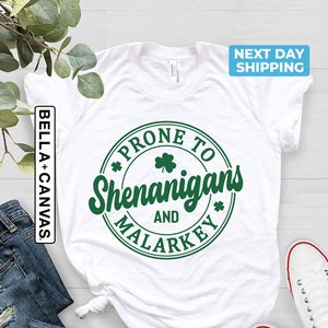 May include: White t-shirt with a green circle graphic that says "Prone to Shenanigans and Malarkey".