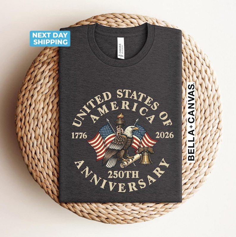 May include: Dark gray t-shirt featuring an eagle, American flags, and the text "United States of America 250th Anniversary 1776-2026". The shirt is made of a soft material and is perfect for celebrating the nation's history.