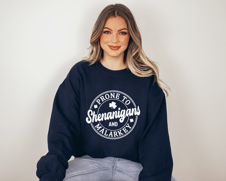 May include: A navy blue sweatshirt with a white circle graphic that says "Prone to Shenanigans and Malarkey" with a shamrock design.