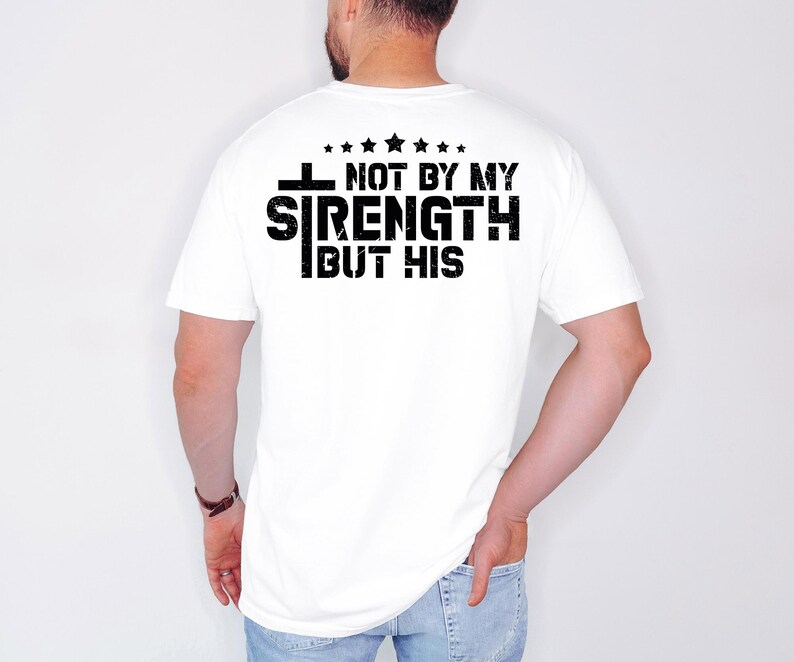 May include: White t-shirt with a black graphic that reads "I Not By My Strength But His" with five stars above the text.