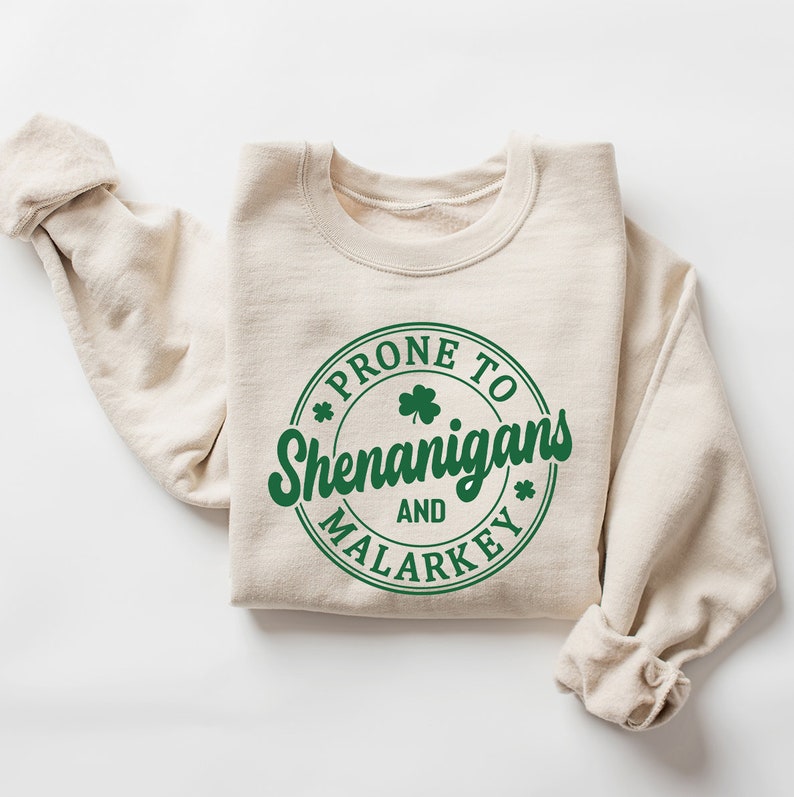May include: A beige sweatshirt with a green circle graphic that says "Prone to Shenanigans and Malarkey" with a shamrock inside the circle.