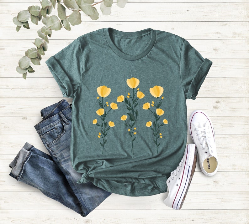 May include: A teal blue t-shirt with a floral design featuring yellow flowers and green stems.