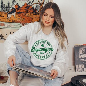 May include: A grey sweatshirt with a green circle graphic that says "Prone to Shenanigans and Malarkey".
