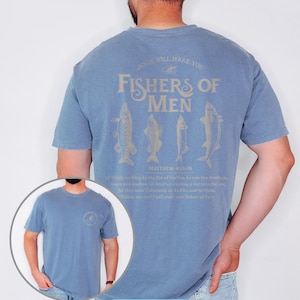 May include: Blue jean short-sleeve t-shirt with the text "JESUS WILL MAKE YOU FISHERS OF MEN" and fish illustrations. The text "MATTHEW 4:18-19" is also printed on the shirt. The shirt has a crew neck and a relaxed fit.
