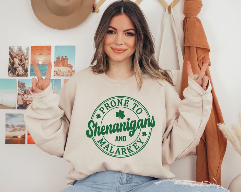 May include: A beige sweatshirt with a green circle graphic that says "Prone to Shenanigans and Malarkey" with a shamrock inside the circle.