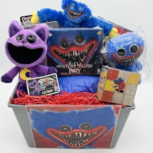 May include: A gray plastic bin filled with Poppy Playtime merchandise, including a purple Catnap plush, a blue Huggy Wuggy plush, a mystery plush box, a small blue plush in plastic, a patterned cube, and a Catnap character card, all resting on red paper shreds.
